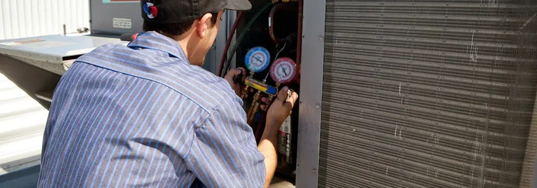 HVAC technician servicing a condenser unit in Edgewood